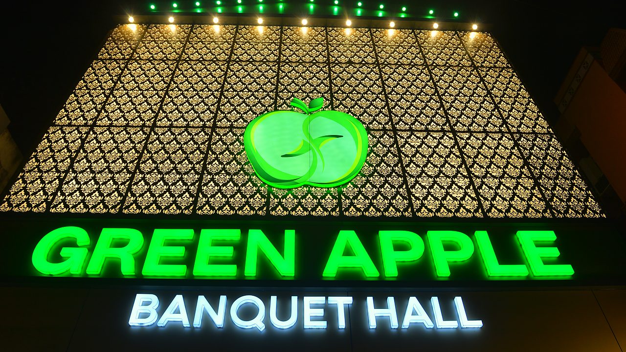 The Green Apple Banquet Hall sign glowing at night